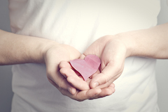 A person holding a heart shaped piece of paper in their hands. 